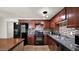 Modern kitchen featuring dark wood cabinets, mosaic tile backsplash, and stainless steel appliances is designed for style and function at 1633 W Andorra Dr, Phoenix, AZ 85029