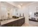 Well-lit bathroom with granite counters, double sinks, and views into the bedroom and walk-in closet at 16694 W Audrey Ln, Surprise, AZ 85387