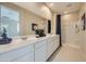 Well-lit main bathroom with double sinks, white cabinets, large mirror and a walk-in shower at 24973 N 174Th Ave, Surprise, AZ 85387
