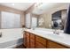 Bright bathroom features double sinks, white cabinets, wood-look tile floors, a soaking tub, and natural light at 25844 W Watkins St, Buckeye, AZ 85326