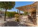 A well-maintained backyard, including a covered patio, desert landscaping and rock beds at 26983 W Runion Dr, Buckeye, AZ 85396