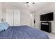 Neutral bedroom features a blue quilt, white closet doors, and a wall-mounted TV at 2926 W Thorn Tree Dr, Phoenix, AZ 85085