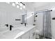 Bathroom featuring double sinks with quartz countertop, black fixtures and a shower with blue patterned curtain at 29374 N 125Th Dr, Peoria, AZ 85383
