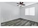 Bright bedroom featuring wood-style floors, fresh white walls, a ceiling fan and a bright window at 29374 N 125Th Dr, Peoria, AZ 85383