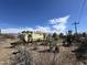 Desert property showing weathered exterior, cacti, and tire amidst arid terrain at 3200 S Mesa Rd, Winkelman, AZ 85192