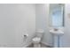 Powder room featuring a pedestal sink, toilet, and large framed mirror at 37051 N Rhinelander Dr, San Tan Valley, AZ 85140