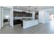 Modern kitchen boasts an island with pendant lights, gray counters, dark cabinets, and gray wood-look tile flooring at 37051 N Rhinelander Dr, San Tan Valley, AZ 85140