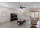 A well-lit living room has a ceiling fan, wood flooring and large windows at 37051 N Rhinelander Dr, San Tan Valley, AZ 85140