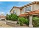 Attractive townhome exterior with a red tile roof, neutral stucco, and lush, mature shrubs at 5808 E Brown Rd # 106, Mesa, AZ 85205