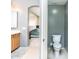 Modern bathroom with neutral tones, featuring a toilet, vanity, and an archway leading to the primary bedroom at 6920 W Tether Trl, Peoria, AZ 85383