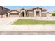 Tan home featuring an arched front door, 2-car garage, decorative wall, and lush green lawn at 6920 W Tether Trl, Peoria, AZ 85383