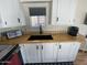 Kitchen sink area with light wood counters, dark sink, and white cabinets at 1118 S Shawnee Dr, Apache Junction, AZ 85119