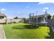 Spacious backyard featuring lush artificial grass, a trampoline, and a fenced dog run at 11607 W Marguerite Ave, Avondale, AZ 85323