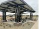Community picnic area under a metal shade structure with picnic tables, benches, and xeriscaping at 15709 W Beryl Ave, Waddell, AZ 85355