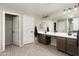 Bright bathroom with dual sinks, a large mirror, and wood-look flooring, offering a functional and modern design at 18040 W Louise Dr, Surprise, AZ 85387