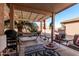 Inviting covered patio with comfortable seating, a hammock, stylish rug, and views of the landscaped backyard at 19975 N Crescent Way, Surprise, AZ 85374