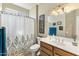 Bathroom with single sink vanity, decorative mirror, shower with patterned curtain, and tile flooring at 20139 N Rawhide Way, Surprise, AZ 85387