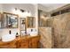Modern bathroom with dual sinks, wood cabinets, and a luxurious stone-walled shower at 21141 E Stirrup St, Queen Creek, AZ 85142