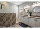 An updated bathroom with double sinks, white cabinets, a decorative-tiled shower, and a window at 2544 W Pumpkin Ridge Dr, Anthem, AZ 85086