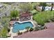 Aerial view of backyard featuring a luxurious pool with rock waterfall, a covered patio with dining, and manicured landscaping at 28689 N 67Th Dr, Peoria, AZ 85383