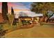 Lush backyard oasis at dusk, featuring a putting green, mature trees, and a cozy pergola-covered outdoor living space at 28689 N 67Th Dr, Peoria, AZ 85383