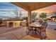 Covered outdoor kitchen with grill, dining table and chairs, near pool and lush landscaping at 28689 N 67Th Dr, Peoria, AZ 85383