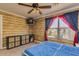 Bedroom featuring faux log walls, a ceiling fan, and a window with red and blue curtains for a rustic, cozy feel at 3397 E Derringer Way, Gilbert, AZ 85297