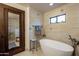 Bright bathroom featuring a standalone tub, tiled walls, modern fixtures, and a wooden door at 36601 N Mule Train Rd # B14, Carefree, AZ 85377