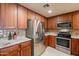 Modern kitchen with stainless steel refrigerator, microwave, and range appliances and wood cabinets at 36601 N Mule Train Rd # B14, Carefree, AZ 85377