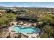 Aerial view of a community pool featuring lounge chairs and desert landscaping against a mountain backdrop at 36601 N Mule Train Rd # B14, Carefree, AZ 85377