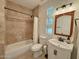 Cozy bathroom with travertine tile, framed mirror, and a shower-tub combo with shower curtain at 3811 N 64Th St, Scottsdale, AZ 85251