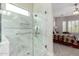 Elegant bathroom with a glass shower, marble tile, and open view to the bedroom at 4086 E Narrowleaf Dr, Gilbert, AZ 85298