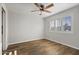 Bedroom with a wood look flooring, white walls, ceiling fan, and window with shutter blinds at 445 S Omaha --, Mesa, AZ 85206