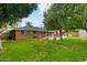 View of a spacious backyard with a lush lawn, mature trees, and a patio area for outdoor seating at 7254 E Vernon Ave, Scottsdale, AZ 85257