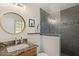 Modern bathroom featuring a granite vanity, round mirror, and tile shower with glass doors at 7254 E Vernon Ave, Scottsdale, AZ 85257