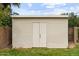 Outdoor storage shed with neutral horizontal siding and white double doors on a grassy lawn at 7254 E Vernon Ave, Scottsdale, AZ 85257