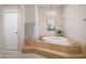 Luxurious bathroom with a soaking tub, travertine tile surround, and modern lighting at 8100 E Camelback Rd # 138, Scottsdale, AZ 85251