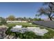 A view of the putting green and sand trap with mature trees, palm trees, and privacy wall at 8817 N 58Th Pl, Paradise Valley, AZ 85253