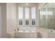 A bright primary bath features a large soaking tub, a glass enclosed shower and shuttered windows at 9440 N Sunset Rdg, Fountain Hills, AZ 85268