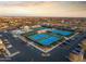 Aerial view of blue tennis courts surrounded by parking and a residential community at sunset at 10843 E Kilarea Ave, Mesa, AZ 85209