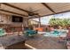 Inviting covered patio area featuring a TV, bar, and dining set adjacent to a sparkling pool and spa at 13146 S 178Th Ave, Goodyear, AZ 85338
