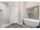 Bright bathroom featuring a glass shower and stand-alone soaking tub with window at 21 W Pecan Pl, Tempe, AZ 85284