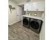 Functional laundry room with modern washer and dryer, white cabinets, and wood-look tile flooring at 2634 E Fountain St, Mesa, AZ 85213