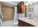 Functional bathroom with a tub, wooden vanity, and neutral tiles offering a clean and practical space at 2910 E Avenida Olivos --, Phoenix, AZ 85016