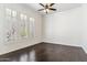 A bright bedroom featuring dark hardwood floors, ceiling fan, and three large windows at 41624 N Anthem Ridge Dr, Anthem, AZ 85086