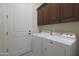 Bright laundry room features white washer and dryer and brown cabinets at 4241 N Pebble Creek Pkwy # 54, Goodyear, AZ 85395