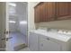 Bright laundry room features white washer and dryer, brown cabinets and garage access at 4241 N Pebble Creek Pkwy # 54, Goodyear, AZ 85395