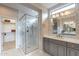 This bathroom offers a glass shower with a white bench and a vanity with gray cabinets, plus a walk-in closet at 623 E Peach Tree St, Queen Creek, AZ 85140