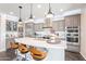 Bright kitchen features stainless steel appliances, a center island with seating and modern pendant lighting at 623 E Peach Tree St, Queen Creek, AZ 85140