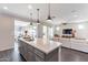 Bright open kitchen with island, stainless sink, modern lighting, and seamless flow into the living room at 623 E Peach Tree St, Queen Creek, AZ 85140